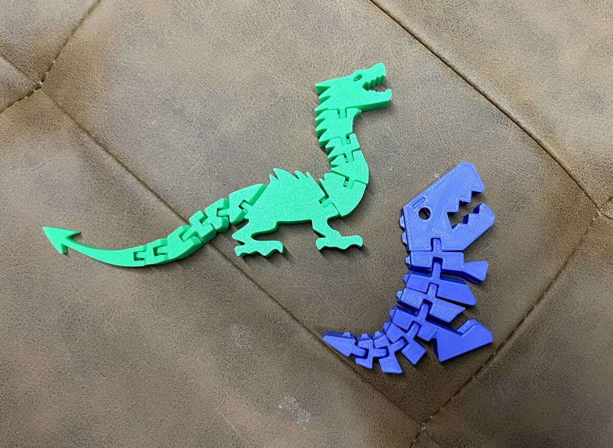 Two articulated flexi dinosaur toys, one green and one blue