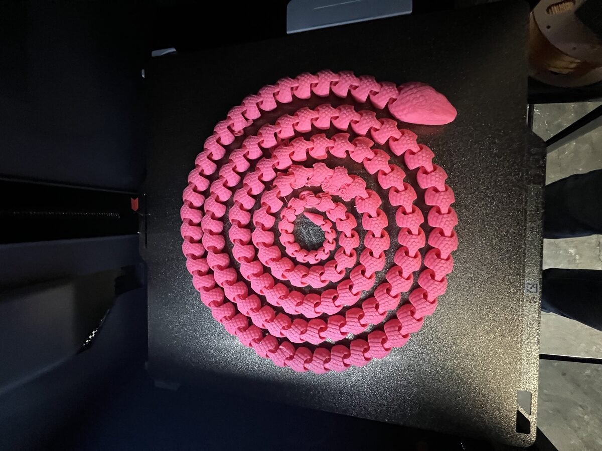 Extra-long articulated pink snake, coiled on the print bed